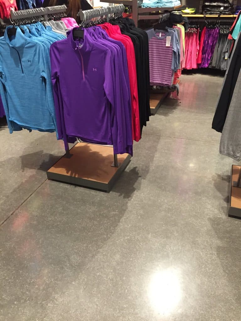 Image of a retail clothing store with polished concrete floors, featuring racks of clothing and a modern, minimalist design aesthetic.