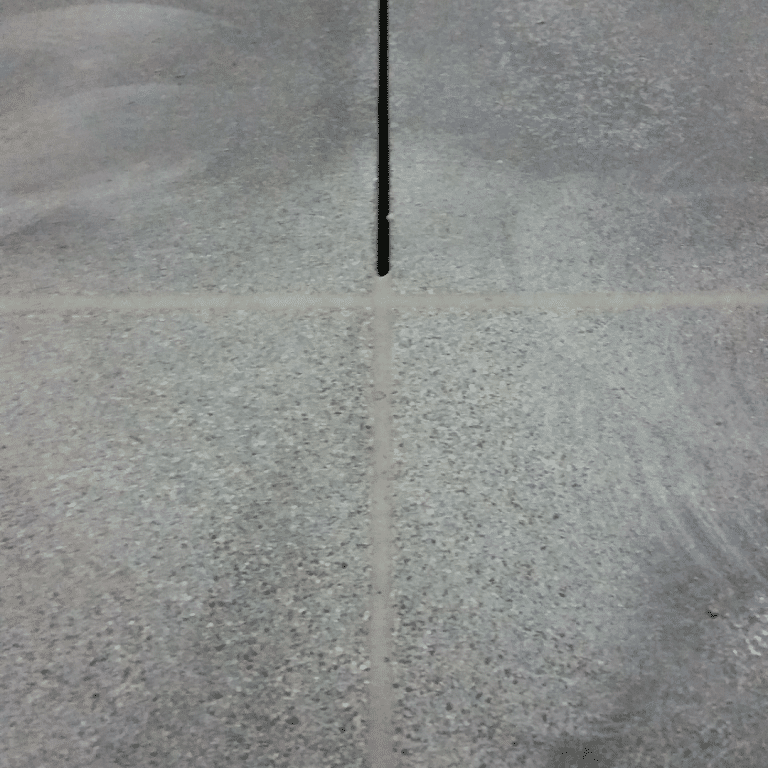 Image of a professional team applying concrete joint fill material into a crack between two concrete slabs to prevent water damage and preserve the integrity of the structure.