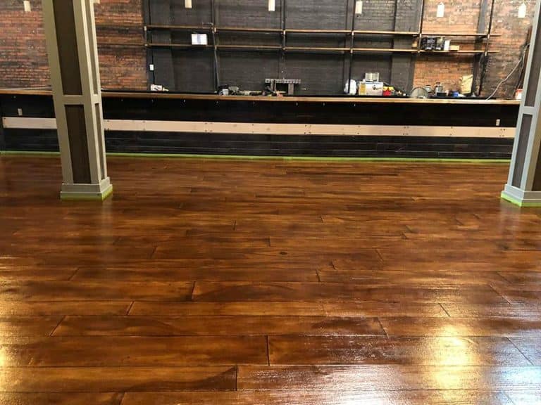 Image of a restaurant floor with a rustic concrete wood design. The flooring features a textured surface with natural variations in color and texture, creating a warm and inviting atmosphere.