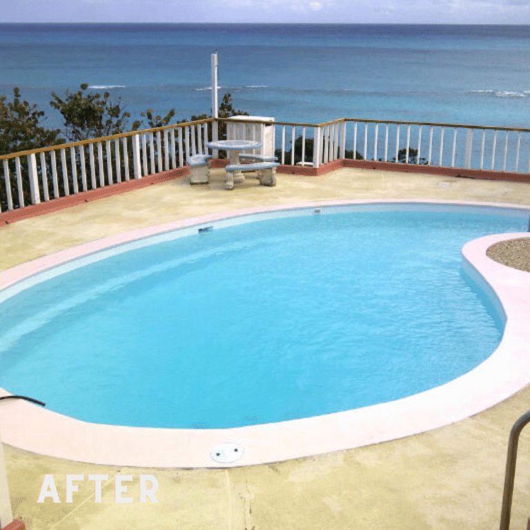 Image of a pool deck with a decorative concrete coating in shades of gray and beige. The surface has a textured appearance with natural variations in color, and is surrounded by lush green foliage and outdoor furniture.