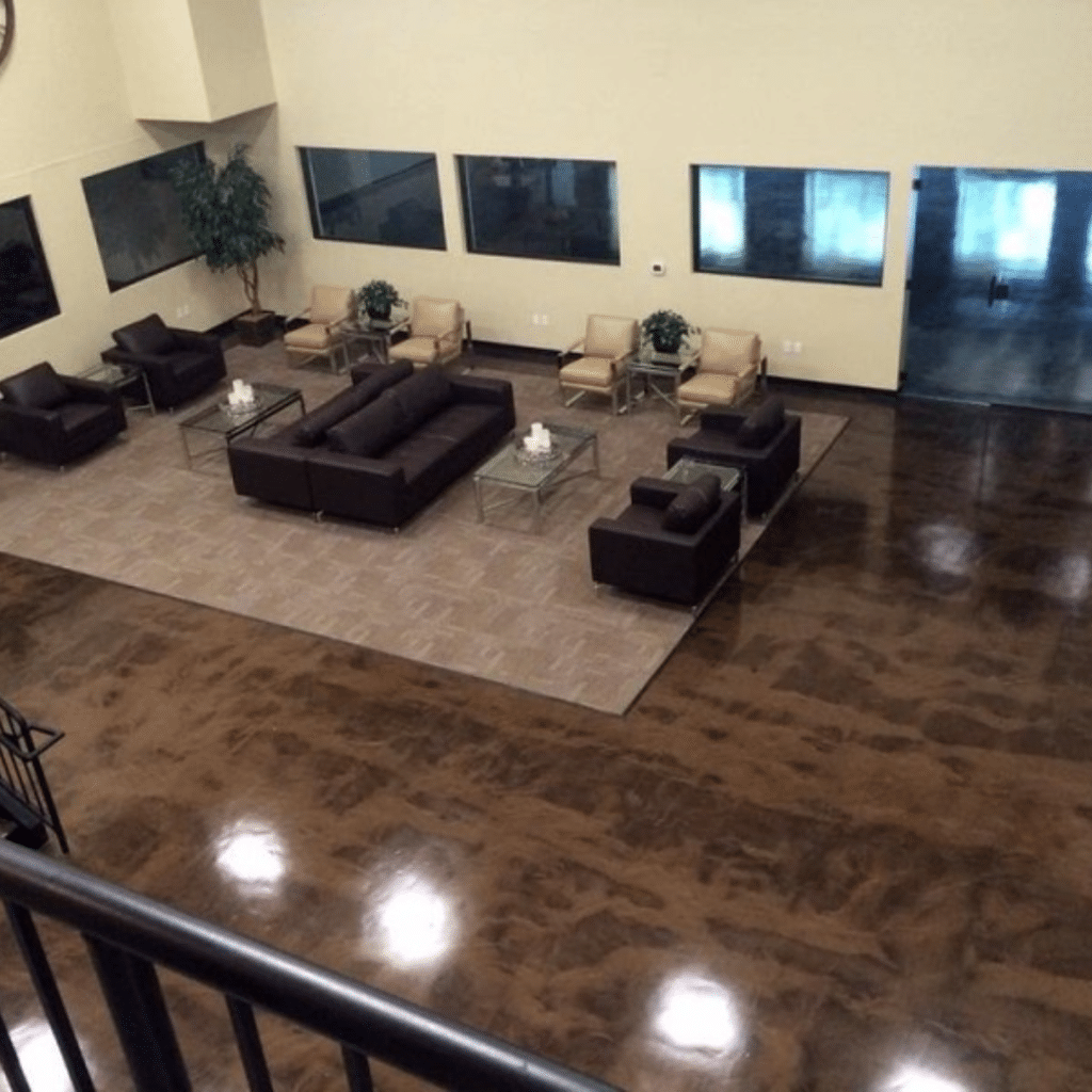 Epoxy flooring in a modern office space with a shiny, polished surface in shades of gray. The floor is seamless and has a reflective quality that adds depth and texture to the space.